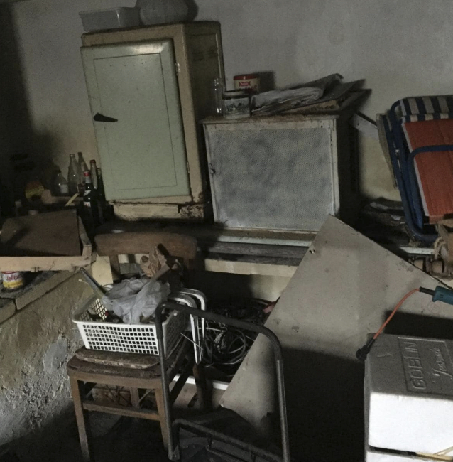 Old appliances and items piled in a dark room